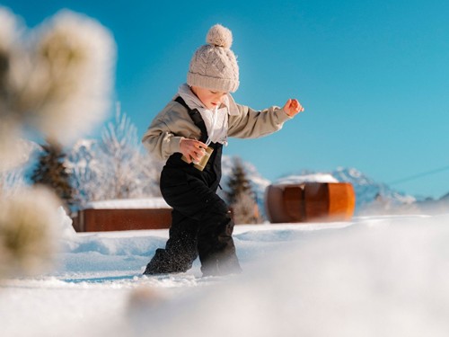 Kind spielt im Schnee – Naturresort Puradies, Leogang Kind läuft durch den Schnee im Naturresort Puradies, Leogang