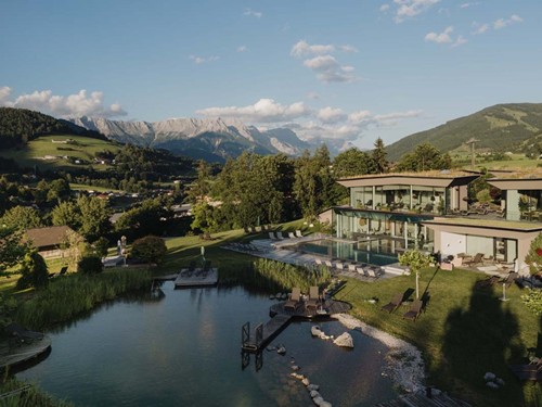 Luftaufnahme – Gesamtansicht von Naturbadeteich und Infinity Pool vor Bergpanorama, Naturresort Puradies, Leogang, Salzburger Land Luftaufnahme von Naturbadeteich und Infinity Pool, Naturresort Puradies in Leogang