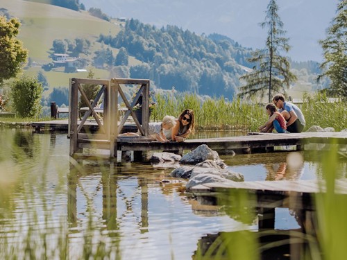 Familie auf Steg am Naturbadeteich, Puradies Leogang