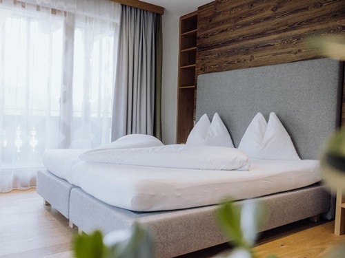Doppelbett mit Holzwand und Balkonzugang, Puradies Leogang