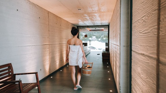Person with Wooden Bucket in the Corridor Between the Saunas at Heaven Spa – Naturresort Puradies, Leogang, Salzburger Land Person with wooden bucket in corridor between the saunas, Puradies Leogang