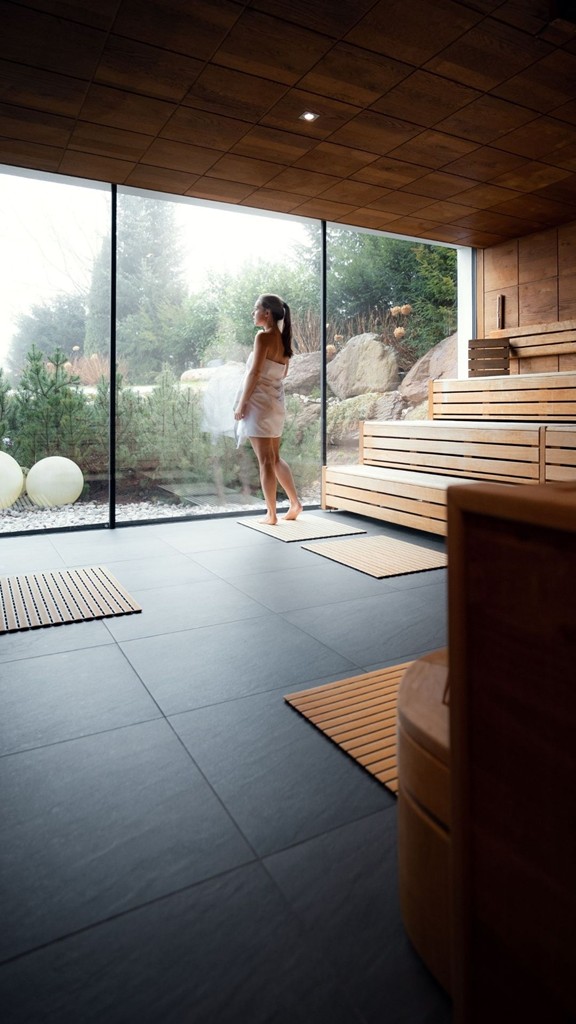 Person steht an der Glasfront der Sauna im Heaven Spa – Naturresort Puradies, Leogang, Salzburger Land Person an der Glasfront der Sauna, Puradies Leogang