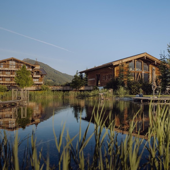 Naturbadeteich mit Traumquartier und Saunahaus im Hintergrund – Naturresort Puradies, Leogang, Salzburger Land Naturbadeteich mit Traumquartier und Saunahaus, Naturresort Puradies in Leogang