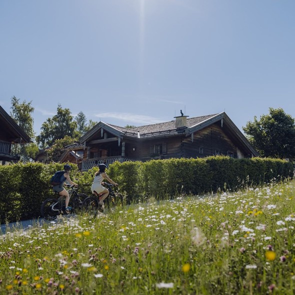 Zwei E-Bikerinnen auf Weg, Chaletdorf im Hintergrund, Naturresort Puradies in Leogang