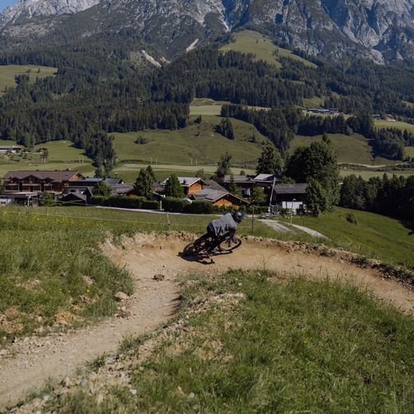 Mountainbiker in Steilkurve vor Bergpanorama, Naturresort Puradies in Leogang