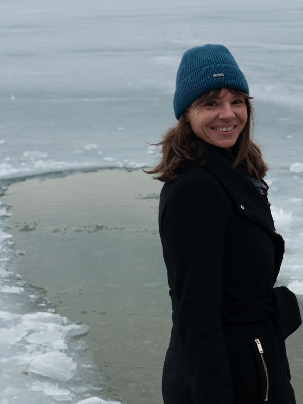 Edith Aigner lächelnd vor einer Eisbadestelle im zugefrorenen Wasser – Retreat, Naturresort Puradies, Leogang, Salzburger Land Edith Aigner vor Eisbadestelle im zugefrorenen Wasser, Retreat Puradies Leogang