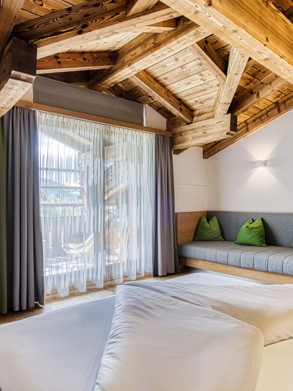 Doppelbett mit Sitzbank und Balkonzugang im Natur Loft im Naturresort Puradies