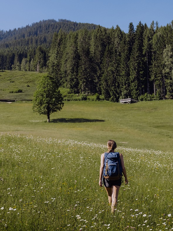 Wanderin auf Blumenwiese am Sonnenplateau, Naturresort Puradies in Leogang