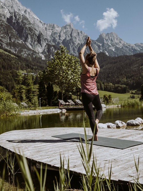 Person in Yoga-Baumhaltung am Naturbadeteich, Naturresort Puradies in Leogang
