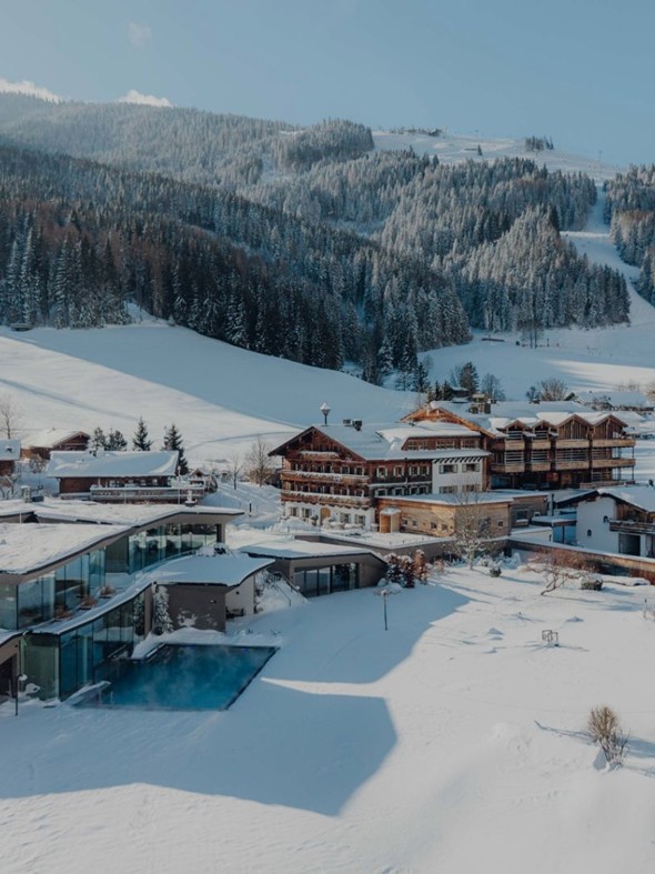 Luftaufnahme der Gesamtanlage im Winter, im Hintergrund Skipiste, Puradies Leogang