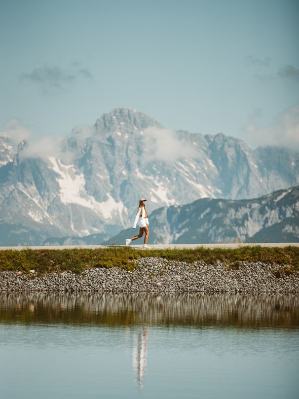 Person am Speicherteich mit Bergpanorama, Leogang
