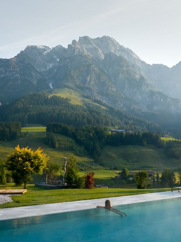 Person im Infinity Pool des Heaven Spa mit Bergpanorama am Morgen – Naturresort Puradies, Leogang, Salzburger Land Person im Infinity Pool des Heaven Spa mit Bergblick, Puradies Leogang