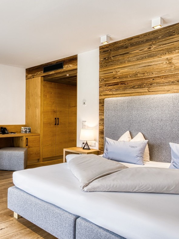 Sitzbank und Doppelbett mit Kleiderschrank in der Deluxe Suite im Naturresort Puradies