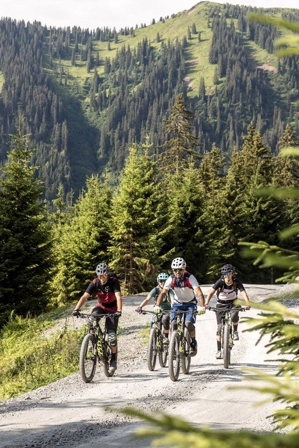 Mountainbiker auf Schotterweg vor Bergwäldern, Naturresort Puradies in Leogang